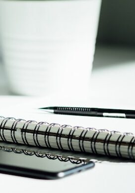 Zu sehen sind: ein Block, ein Stift und ein Handy.